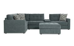 a gray sectional couch and ottoman with pillows