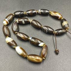 A gorgeous strand of vintage banded agate beads ,each bead has been cherry picked for its distinct high quality all of the long banded agate beads were collected in India in the 1970 Beads will display natural crystalline banding and rang in color from light browns to mostly black ,the large focal is particular beautiful Vintage Agate Beaded Necklace With Oval Beads, Vintage Agate Oval Beads, Brown Large Oval Beads, Gems, And Cabochons, Large Brown Agate Beads, Brown Large Agate Beads, Brown Polished Oval Beads, Hand-strung Oval Agate Beads, Hand-strung Brown Agate Beads, Polished Oval Agate Beads