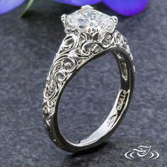 a close up of a ring on a table with flowers in the background