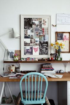 a blue chair sitting in front of a desk with pictures on the wall above it