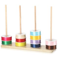 several spools of colored thread are on a wooden stand with toothpicks