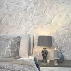 a bedroom with marble wallpaper and white bedding, two lamps on nightstands