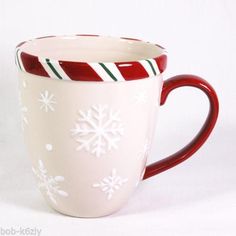 a red and white coffee cup with snowflakes on it's rim is sitting in front of a white background