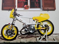 a yellow and white motor bike parked in front of a window with red shutters