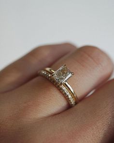 a woman's hand with a diamond ring on top of her finger and an engagement band