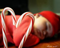 a baby laying on top of a wooden table next to candy canes in the shape of a heart