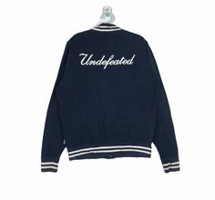 "PLEASE CONTACT TO ME WITH ANY QUESTION BEFORE BUYING.. PLEASE READ THE DESCRIPTION AND POLICIES BEFORE BUYING. TAG BRAND :-Undefeated SIZE ON TAG : Medium ACTUAL SIZE MEASUREMENT :- ARM PIT TO ARM PIT :-22.5\"incher BACK COLLAR TO HEM:-26\"incher PLEASE COMPARE THE MEASUREMENT WITH YOUR GARMENT CONDITION :8/10..(refer picture) COLOUR :-View Pic.. MATERIAL:-Cotton Kindly read my shipping and policies. SHIP WORLDWIDE VIA DHL GLOBAL MAIL. ⚫️Takes 14 working days to arrive. ⚫️Safely trackin number= Casual Cotton Varsity Jacket For College, Cotton Varsity Jacket With Crew Neck For Streetwear, Cotton Varsity Jacket With Crew Neck For College, Cotton Varsity Jacket With Embroidered Logo For College, Crew Neck Cotton Varsity Jacket For College, Throwback Cotton Varsity Jacket For Winter, Casual Crew Neck Varsity Jacket For Sports Events, Cotton Varsity Jacket With Crew Neck For Sports Events, Casual Cotton Varsity Jacket With Letter Print