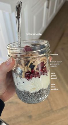 a person holding a spoon in a jar filled with cereal and other things to eat