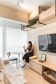 a woman sitting on a couch in front of a table with a tv mounted above it