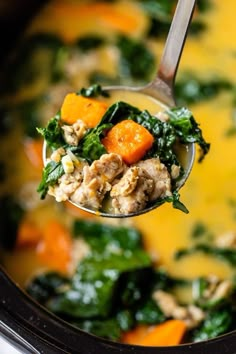 a spoon full of soup with carrots and spinach