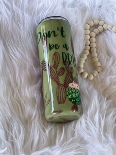 a can that is sitting on top of a white fur covered floor next to a beaded necklace