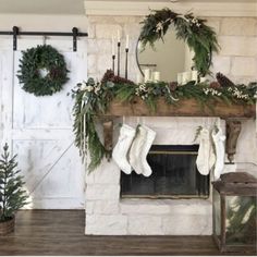 a fireplace decorated for christmas with stockings and wreaths