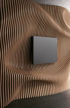 a square object is mounted on the wall in front of a wave pattern design that looks like wood