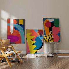 an empty room with paintings on the wall and a chair in the foreground next to it