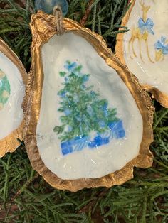 three pieces of art that look like seashells with trees painted on the inside