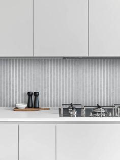 a kitchen with white cupboards and countertops has black accents on the backsplash