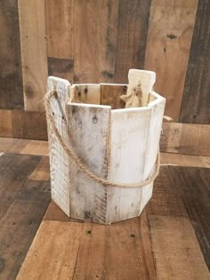 a wooden bucket with rope tied around it on top of a wooden floor in front of wood planks