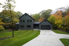 a large gray house in the middle of a wooded area with trees and grass around it