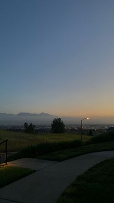 the sun is setting over an open field with mountains in the background