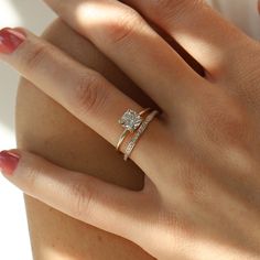 a woman's hand with a diamond ring on her left wrist and the other hand holding an engagement ring