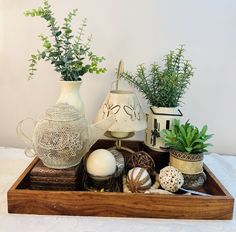 a tray with vases, plants and other decorative items in it on a table