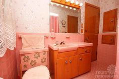 a bathroom with pink walls and flooring has a toilet, sink, mirror and shower curtain