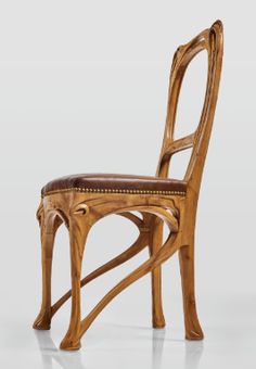 a wooden chair with a leather seat and back rest on a white surface, in front of a plain background