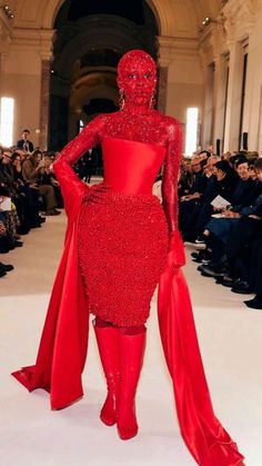 a woman in a red dress walking down a runway