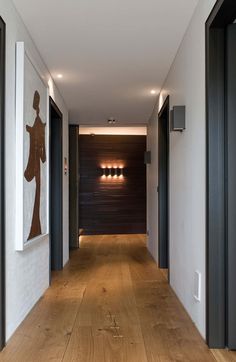 an empty hallway with wood flooring and artwork hanging on the wall above it's doors