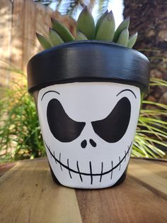 a potted plant with a skeleton face painted on it's side sitting on a table