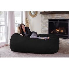 a woman sitting on a bean bag chair in front of a fireplace