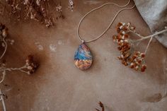 "This piece of nature inspired jewelry is designed to look like it encases tiny mountains set in front of a colorful iridescent galaxy. The pendant is shaped and polished by hand from natural wood, resin and lab-made opal. The high quality finish makes the wood silky smooth and the resin glass like. The piece shown in the picture is to show the shape, color and style of the pendant you are buying. There may be slight variation in the color and appearance of the pendant you receive as each piece Adjustable Nature-inspired Necklace For Gift, Nature-inspired Jewelry With Unique Variations As Gift, Nature-inspired Hypoallergenic Jewelry For Gifts, Minimalist Handmade Necklace For Keepsake, Bohemian Hypoallergenic Necklace For Gift, Bohemian Hypoallergenic Necklace Gift, Hypoallergenic Bohemian Necklace Gift, Minimalist Handmade Keepsake Necklace, Nature-inspired Teardrop Pendant Jewelry Gift