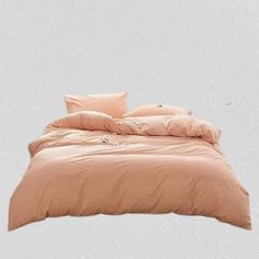 the bed is made up with peach colored sheets and pillows on top of each other