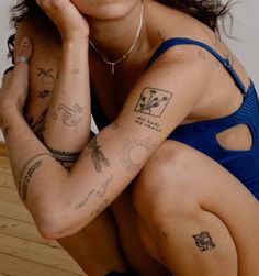 a woman sitting on the floor with tattoos on her arms