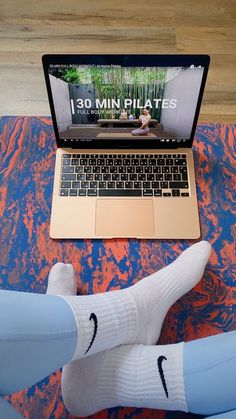 a person sitting on a bed with their feet up in front of a laptop