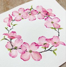 a watercolor painting of pink flowers in a circle on white paper with green leaves