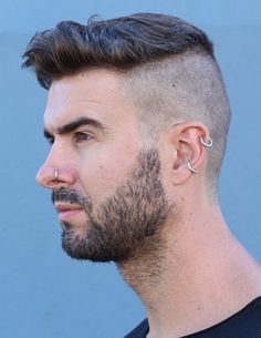 a close up of a person with a shaved hair and piercings on his ear