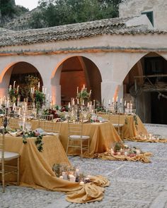 an outdoor setting with tables and chairs covered in yellow cloths, candles and flowers