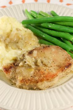 a white plate topped with meat, mashed potatoes and green beans