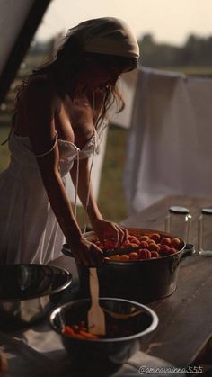 a woman in white dress preparing food on top of a wooden table with utensils