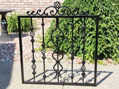 a wrought iron gate is shown in front of a brick wall and green shrubbery