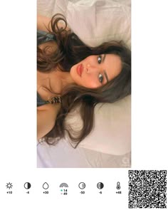 a woman laying on top of a bed next to a qr code