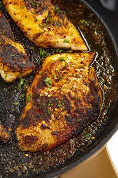 three pieces of chicken cooking in a skillet