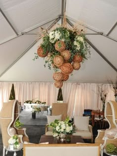 the inside of a tent with chairs, tables and flowers hanging from it's ceiling