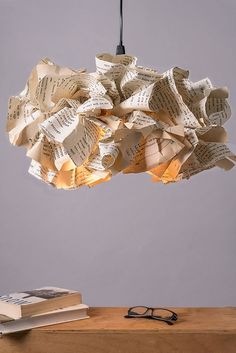 a lamp made out of books hanging from a light fixture over a table with glasses on it