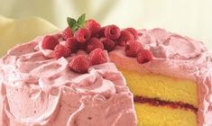 a cake with pink frosting and raspberries is on a white platter