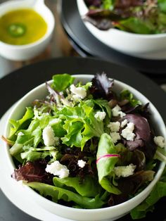 a salad with feta cheese and lettuce in a white bowl on a black plate