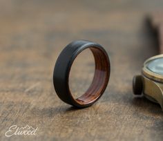 a wooden ring sitting on top of a table next to a watch face with a leather band