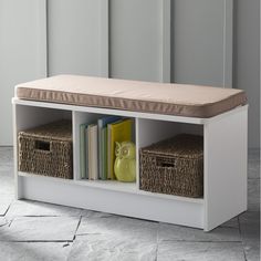 a white storage bench with baskets and books