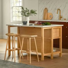 a kitchen island with two stools next to it and a potted plant on the counter